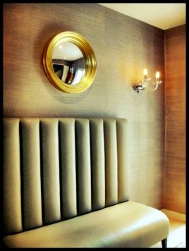 gold convex mirror by Omelo Mirrors hanging above a sofa