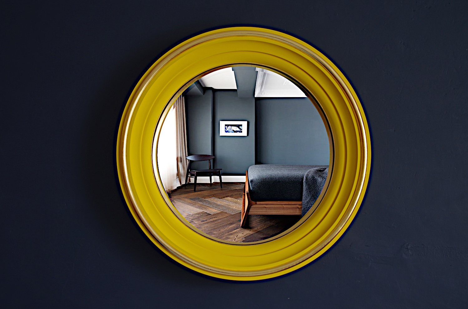 convex mirror with yellow frame hanging on dark blue wall image